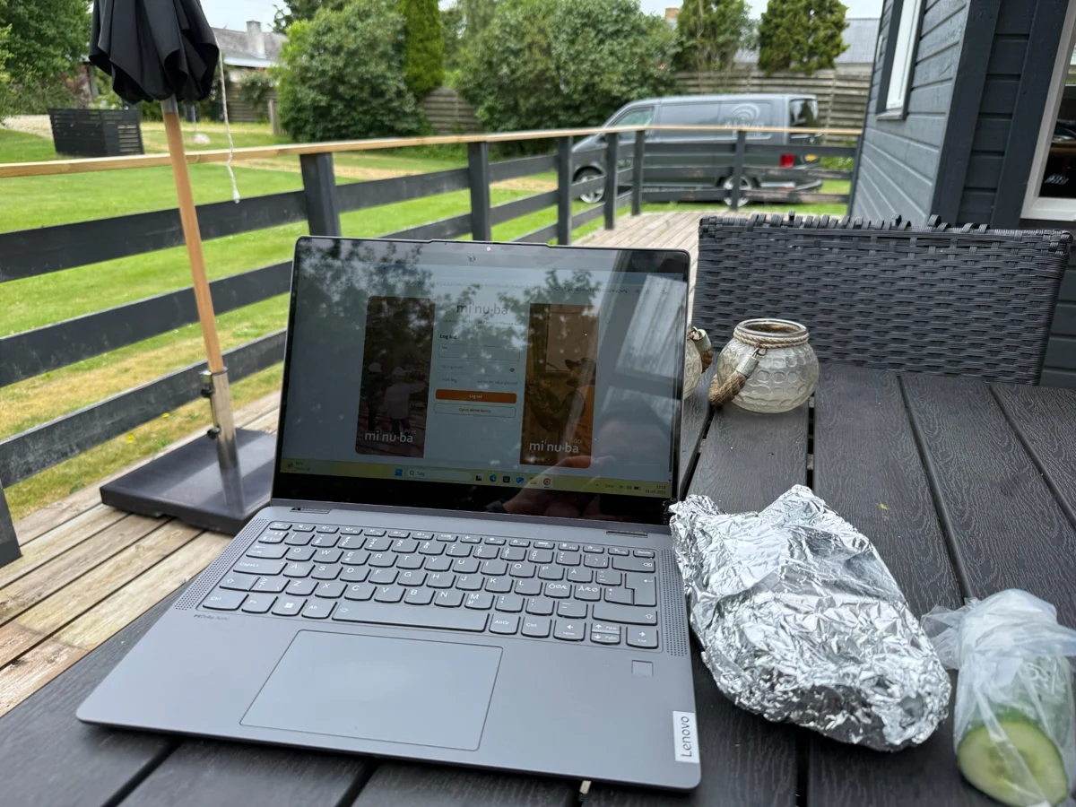 Arbejdscomputer på et havebord med Alarmtekniks servicevogn i baggrunden